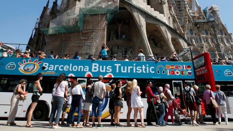 people-queue-up-at-a-city-tour-bus-stop-in-front-of-the-basilica-sagrada-familia-in-barcelona_5370533